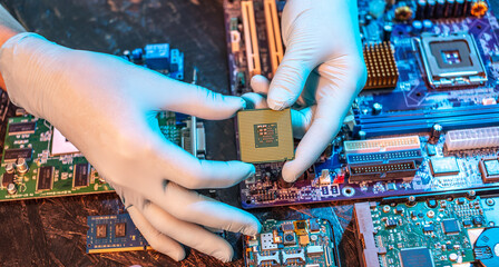 Engineer's gloved hand is holding the CPU chip on the background of the motherboard. High-tech hardware microelectronics