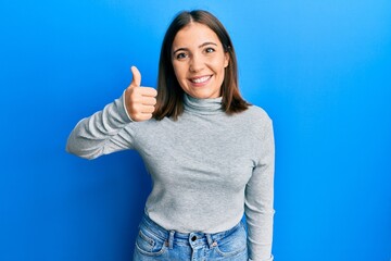 Young beautiful woman wearing casual turtleneck sweater smiling happy and positive, thumb up doing excellent and approval sign