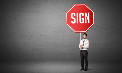 Obraz premium Young business person holding road sign