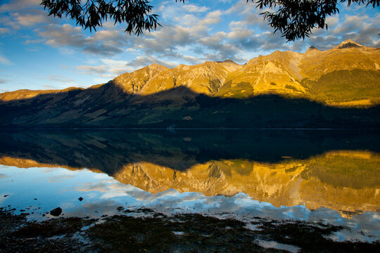 Early AM sun lights the  high peaks of the Southern Alps creating mirror-like reflections on Lake Wakatipu near Glenorchy in New Zealand's South Island.    