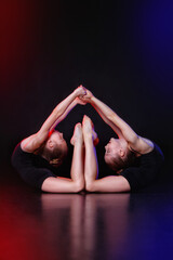 Touch. Two young gymnasts together in neon colored lights on a black background. The concept of gymnastics and modern choreography. Creative art photo.