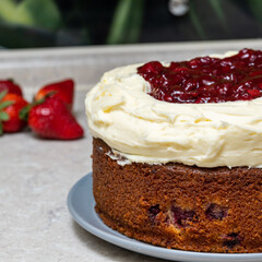 cherry cake with cream cheese and cherries on cream, on a stone table top on a background of strawberries.