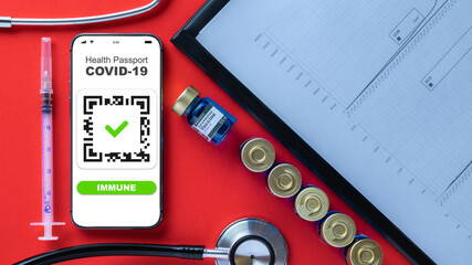 Immune passport. Coronavirus immunity certificate or vaccine passport on smartphone screen with doctor stethoscope, healthcare charts, syringe and medical equipment on hospital red background.