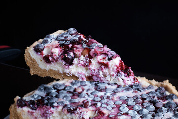 prepared berry pie on the table in the kitchen the cook cuts a piece of a separate blurred background