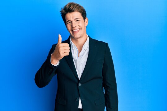 Handsome caucasian man wearing business suit and tie smiling happy and positive, thumb up doing excellent and approval sign
