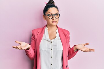 Beautiful middle eastern woman wearing business jacket and glasses clueless and confused with open...