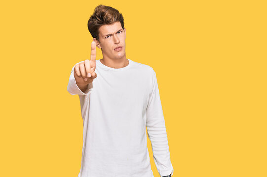 Handsome caucasian man wearing casual white sweater pointing with finger up and angry expression, showing no gesture