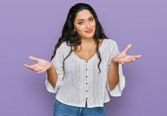 Brunette young woman wearing casual clothes clueless and confused expression with arms and hands...