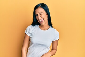 Obraz premium Beautiful hispanic woman wearing casual white tshirt winking looking at the camera with sexy expression, cheerful and happy face.