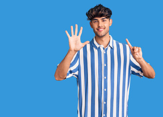 Fototapeta premium Young hispanic man wearing casual clothes showing and pointing up with fingers number six while smiling confident and happy.