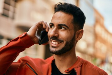 Young hispanic man smiling happy talking on the smartphone at the city.