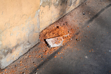 Old wall with pieces of broken brick on the asphalt