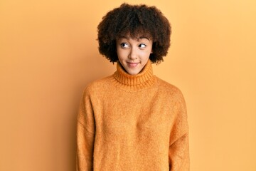 Young hispanic girl wearing wool winter sweater smiling looking to the side and staring away thinking.