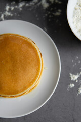 baking cupcakes composition. eggs, cupcakes, flour, milk, whisk and spoon on a dark background. Close up of baked pancakes on a white plate.
