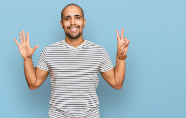 Naklejka premium Hispanic adult man wearing casual clothes showing and pointing up with fingers number seven while smiling confident and happy.