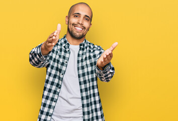 Naklejka premium Hispanic adult man wearing casual clothes looking at the camera smiling with open arms for hug. cheerful expression embracing happiness.