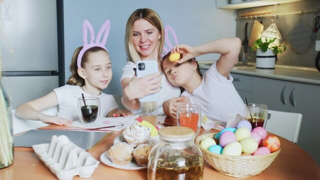 Happy family preparing for Easter. Cute little girls wearing bunny ears takes selfie photo on Easter day.