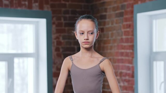 A little skinny ballerina girl training movements in the studio 