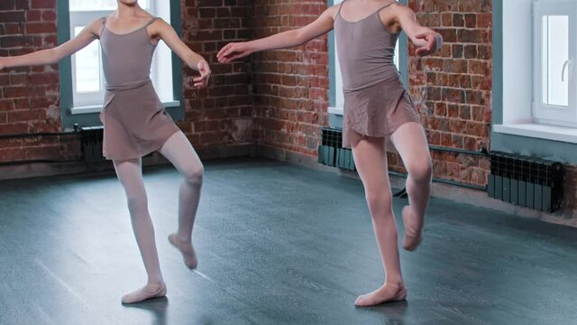 Two ballerina girls training synchronized movements in the studio 