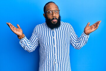 Young african american man wearing business style clueless and confused with open arms, no idea and...