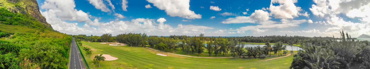 Fototapeta na wymiar Golf course along a beautiful mountain and road, aerial panorama