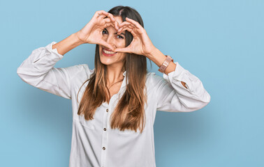 Young beautiful woman wearing casual clothes doing heart shape with hand and fingers smiling looking through sign