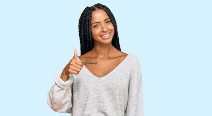 Beautiful hispanic woman wearing casual clothes doing happy thumbs up gesture with hand. approving expression looking at the camera showing success.