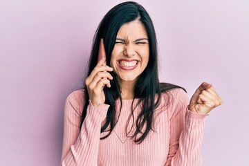 Young hispanic woman having conversation talking on the smartphone screaming proud, celebrating victory and success very excited with raised arm