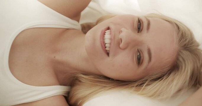 Blonde Model with a Teasing Smile Laying in Bed on a Sunny Day