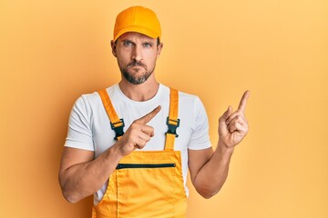 Young handsome man wearing handyman uniform pointing to the side skeptic and nervous, frowning upset because of problem. negative person.