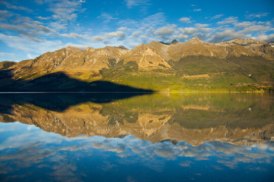Early AM sun lights the  high peaks of the Southern Alps creating mirror-like reflections on Lake Wakatipu near Glenorchy in New Zealand's South Island.    