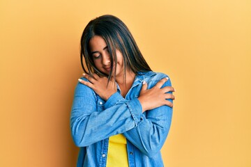 Young latin girl wearing casual clothes hugging oneself happy and positive, smiling confident. self...