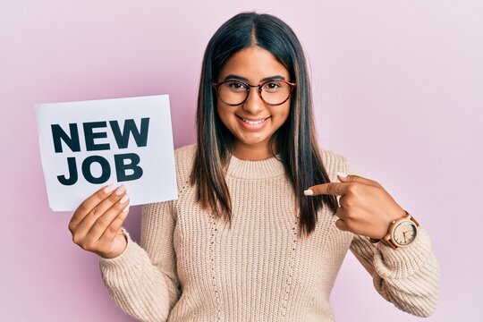 Young latin girl holding new job message on paper pointing finger to one self smiling happy and proud