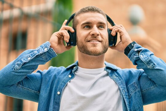 Young caucasian man smiling happy using headphones at the city.