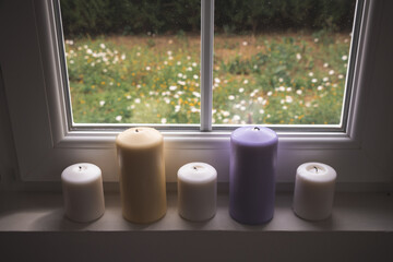 Colorful Candles next to a window with spring view