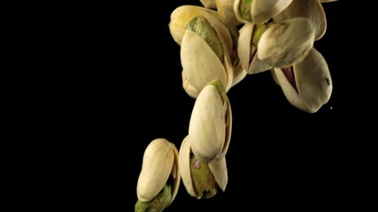 Macro shot in slow motion of falling pistachios over black background