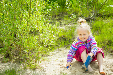 kid playing in the sand and with cameos on the riverbank, selective focus