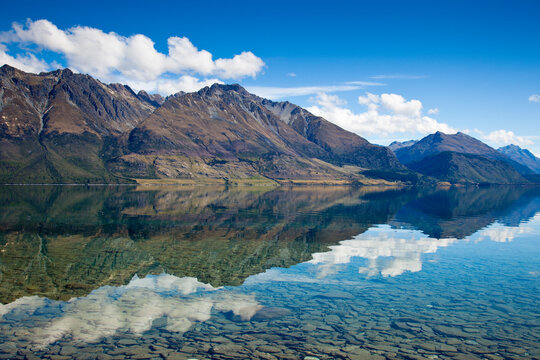 High-noon sun on the  high peaks of the Southern Alps creates mirror-like reflections on Lake Wakatipu near Glenorchy in New Zealand's South Island.    
