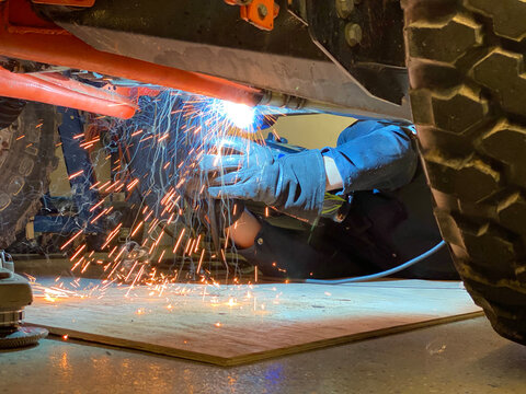 Welder welding on a offroad vehicle in a garage shop