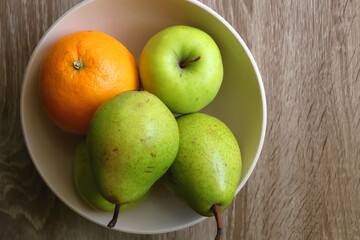 Bowl with pears, appples and oranges on a table. Flat lay.