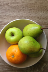 Bowl with pears, appples and oranges on a table. Flat lay.