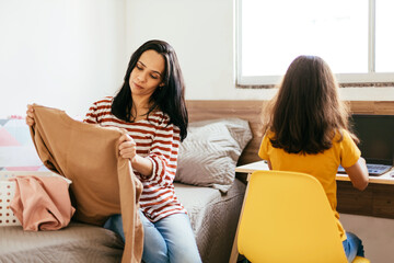 Single parenthood. Mother doing household chores with preteen daughter around.