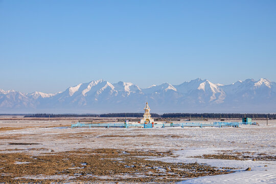 Buddhist stupa Decorated with Prayer Flags against Background of Snowy Peaks of Eastern Sayan Mountains on Sunny Winter Day in Buryatia, Siberia, Baikal Region. Tunka Valley