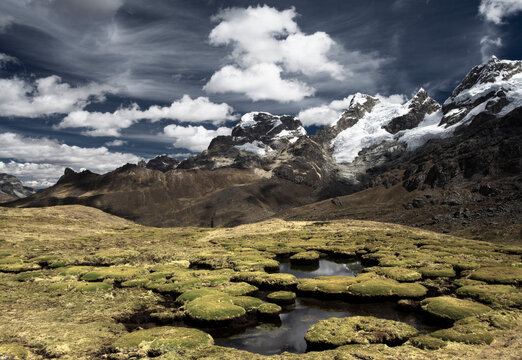 Mountain peaks and what looks like giant moss covered toad stools in a surreal looking landscape located in the Cordillera Huayhuash in the Andes Mountains of Peru.      