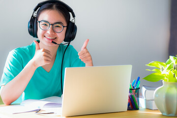 Portrait Asian young woman student glasses headphones happy study smile looking two thumbs up online class college learning internet education teenage girl work distance on a laptop computer from home