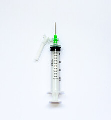 Hypodermic syringe with green needle on white background top view. Science in times of Coronavirus Covid-19 pandemic. Vertical framing