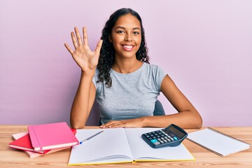 Young african american girl accountant working at the office showing and pointing up with fingers number five while smiling confident and happy.