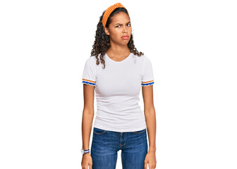 Young african american girl wearing casual clothes skeptic and nervous, frowning upset because of...