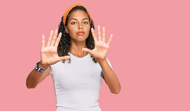 Young african american girl wearing casual clothes doing frame using hands palms and fingers, camera perspective