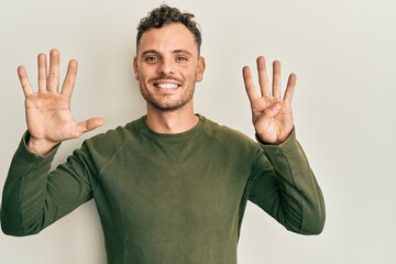 Young hispanic man wearing casual clothes showing and pointing up with fingers number nine while...